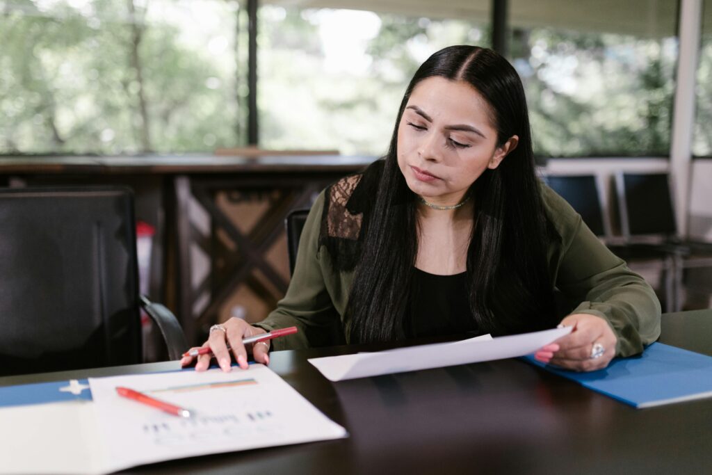Professional woman in office setting studying documents with concentration.